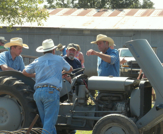 Denim-clad farmers gather around a tractor to discuss issues important to agriculture.