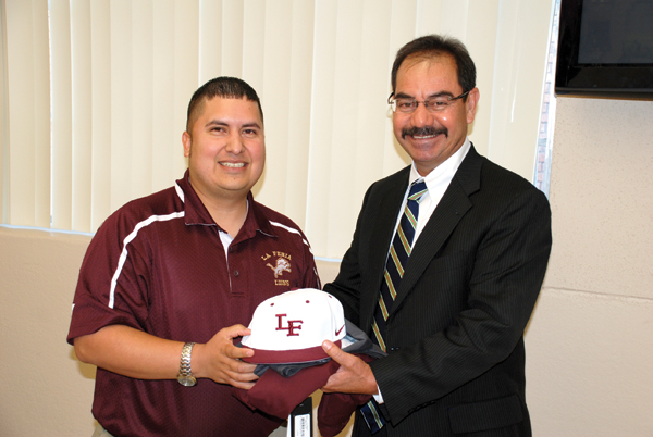 La Feria School Board President Juan Briones presents a Lion hat and shirt to newly hired Superintendent Rey Villarreal