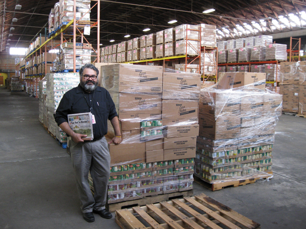  Omar stands beside stacks of donated nutritious food ready for distribution. 