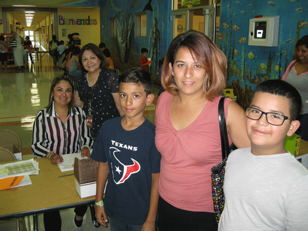 Carina Trujillo comes to sign up her two boys Abel and Hector. Principal Isabel Villarreal and Anna Castellano, PEIM clerk look on.