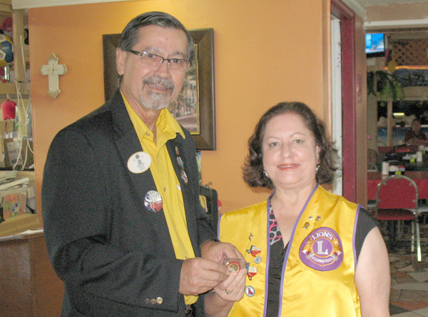 Picture of District Governor, Juan Lopez, presenting commemorative coin to Lion Sylvia Carlin