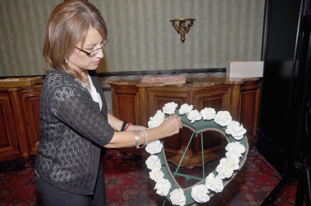 Katie McCarty, Director of Volunteer Services for Valley Baptist Health System, arranges white flowers on a heart-shaped wreath, in remembrance of babies who passed away before or shortly after birth, during an annual memorial service for grieving parents. 