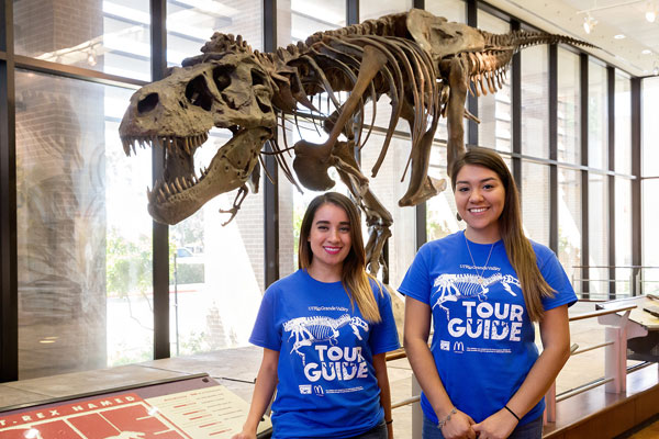 UTRGV student tour guides Valeria Salinas and Gabrielle Silva in front of Sue the Tyrannosaurus rex exhibit, following the press conference launch for the 15th anniversary of HESTEC 2016, on Thursday, Sep. 29, at the Visitors Center on the Edinburg Campus. (UTRGV Photo by Paul Chouy)